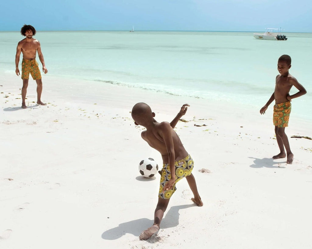 Man and kids in vibrant Print Swim Shorts playing by Zanzibar's seaside
